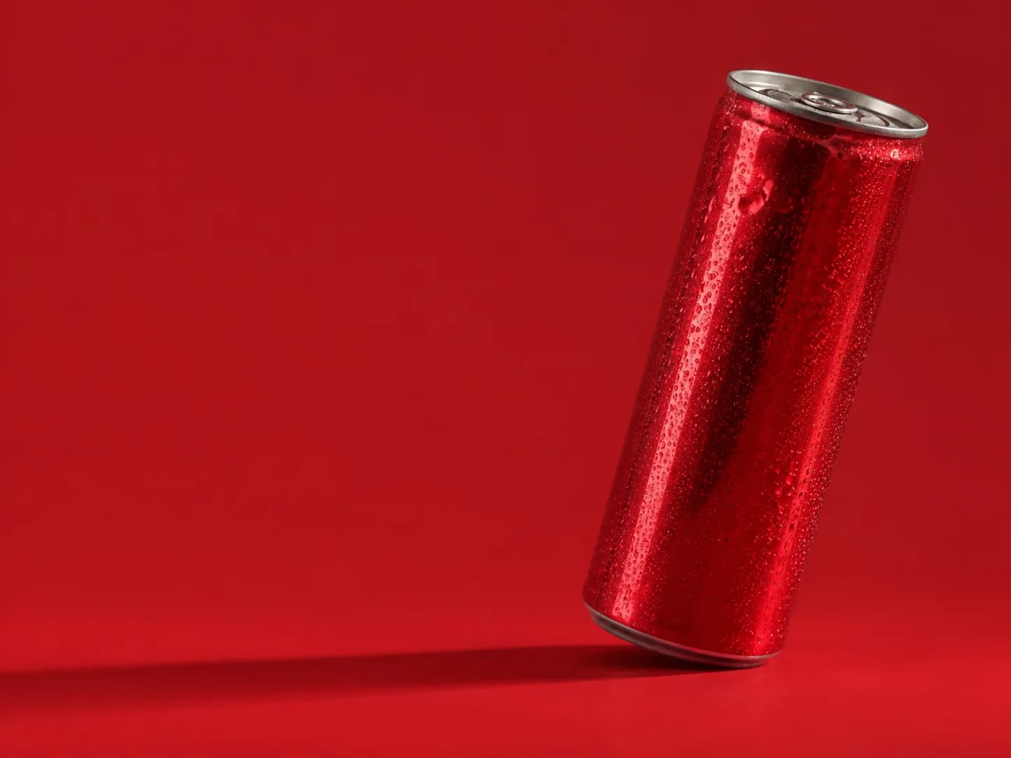 Fictional unbranded red drinks can with condensation, photographed against a red background