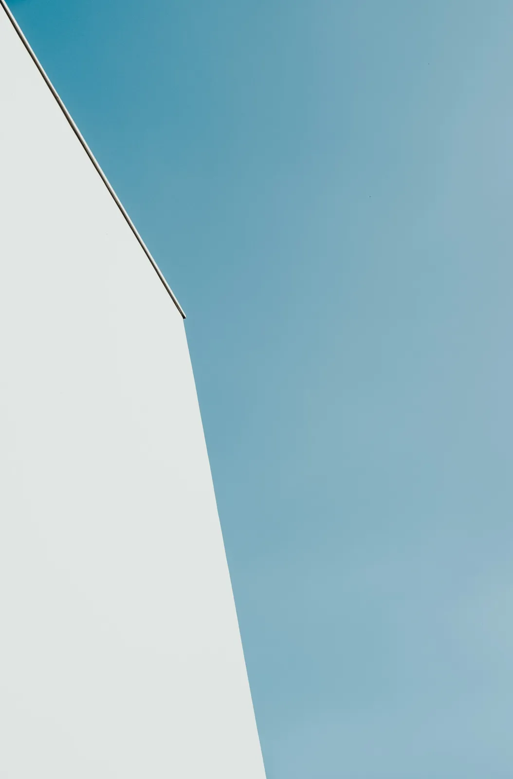 White concrete building under teal sky