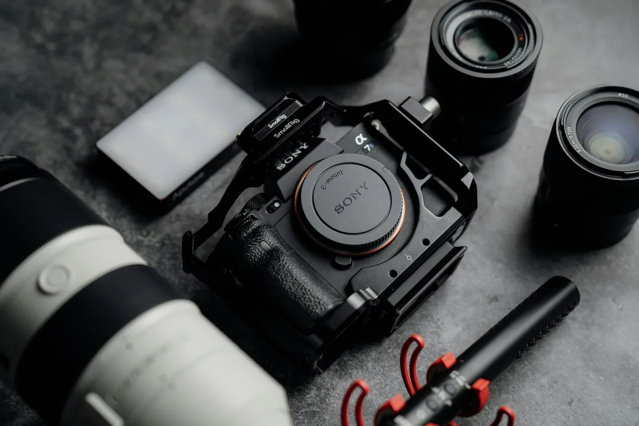 A camera, a camera lens, a pen, and other items on a table