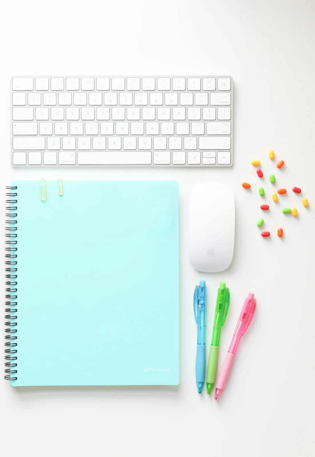White keyboard, mouse and colourful stationery on a mint desk